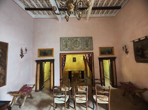 Una habitación con una larga mesa, sillas, un candelabro y cuadros en las paredes.