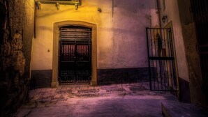 Un bâtiment doté d’une grande entrée en arc de cercle, d’un balcon avec un luminaire et d’une grille.