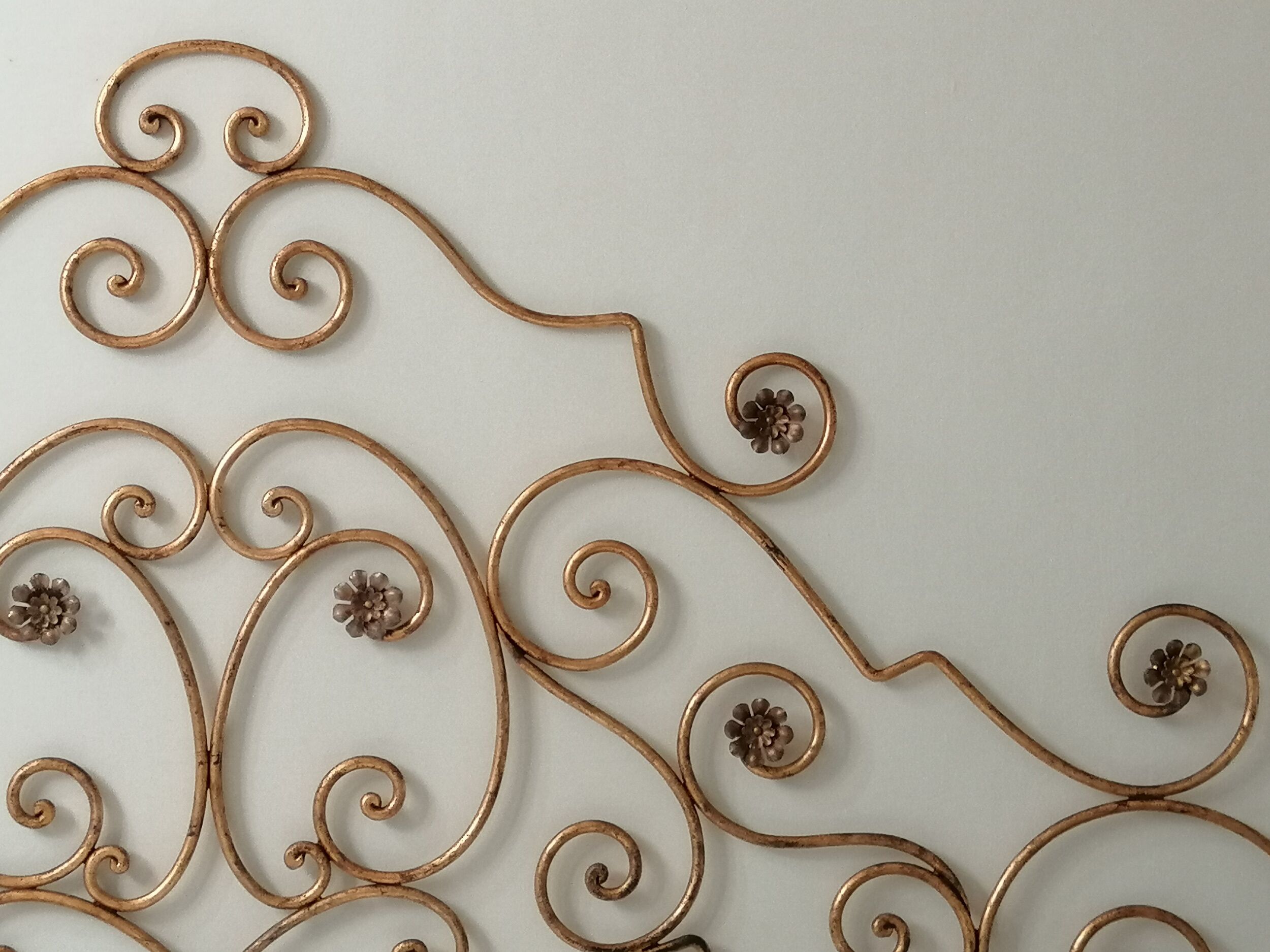 Een decoratief metalen wandkunstwerk met bloemmotieven.
