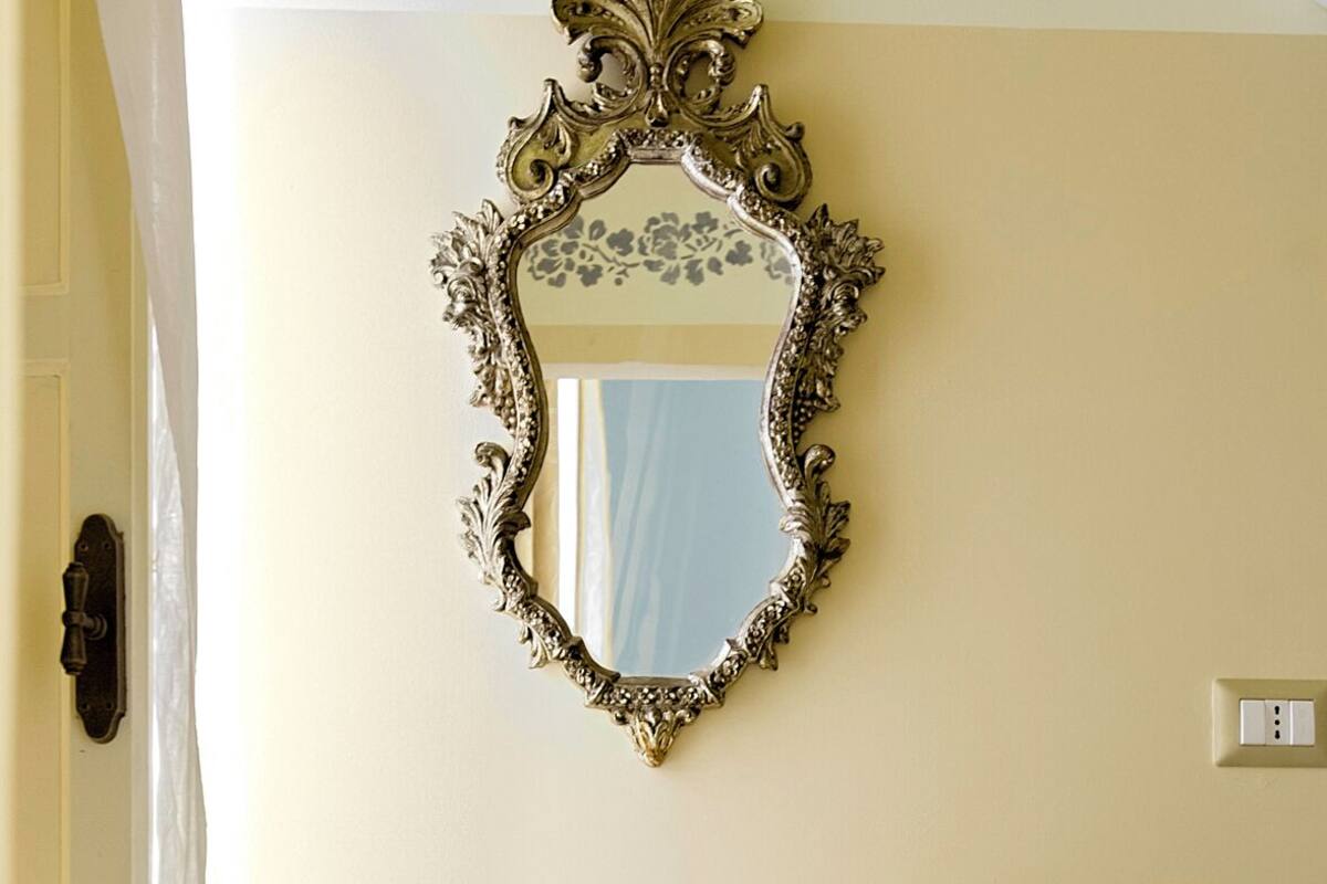 Een badkamer met een witte wastafel, een decoratieve spiegel en gele handdoeken.