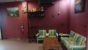 A living room with a sofa, two armchairs, a wooden coffee table, a fireplace, and a shelf with decorative items. - GW Furama Apartment (Kuching)