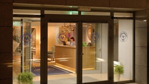 A hotel entrance with a reception desk, glass doors, and a logo on the walls. - Marina Club Hotel (Gdansk)