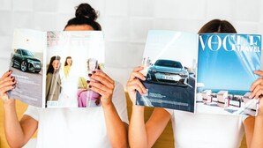 Two individuals reading magazines on a bed with white bedding and a striped skirt. - Marina Club Hotel (Gdansk)
