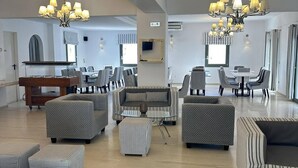 A spacious living area with a pool table, multiple seating options including sofas and ottomans, and two chandeliers.