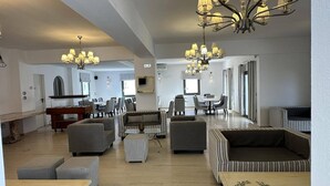 A spacious living area with multiple seating options, a dining table, and a chandelier.