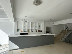 A modern kitchen with a central island, built-in shelving, and a staircase leading to another level.