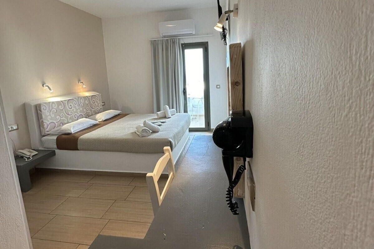 Habitación de hotel con cama, mesitas de noche, aire acondicionado y secador de pelo.