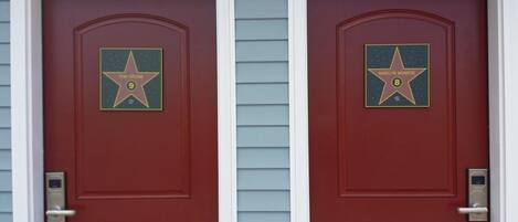 Dos puertas rojas con placas en forma de estrella, una con la leyenda "Tom Cruise" y la otra "Marilyn Monroe".