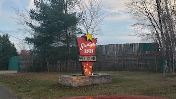 Une enseigne de l’hôtel Starlight Inn avec le message « Bienvenue », entourée d’une clôture en bois et d’arbres.