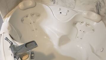 Une baignoire dotée de plusieurs jets, d’un pommeau de douche à main et d’un panneau de commande.