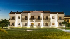 A multi-story hotel with a central courtyard, balconies on each floor, and a well-lit exterior. - Stemma Hotel (Corfu)