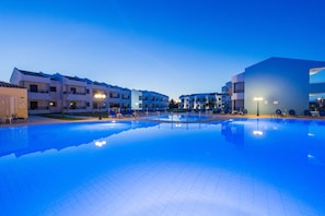 A swimming pool with lounge chairs and a building with balconies. - Stemma Hotel (Corfu)