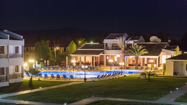 A pool area with lounge chairs and a building with multiple floors and balconies. - Stemma Hotel (Corfu)