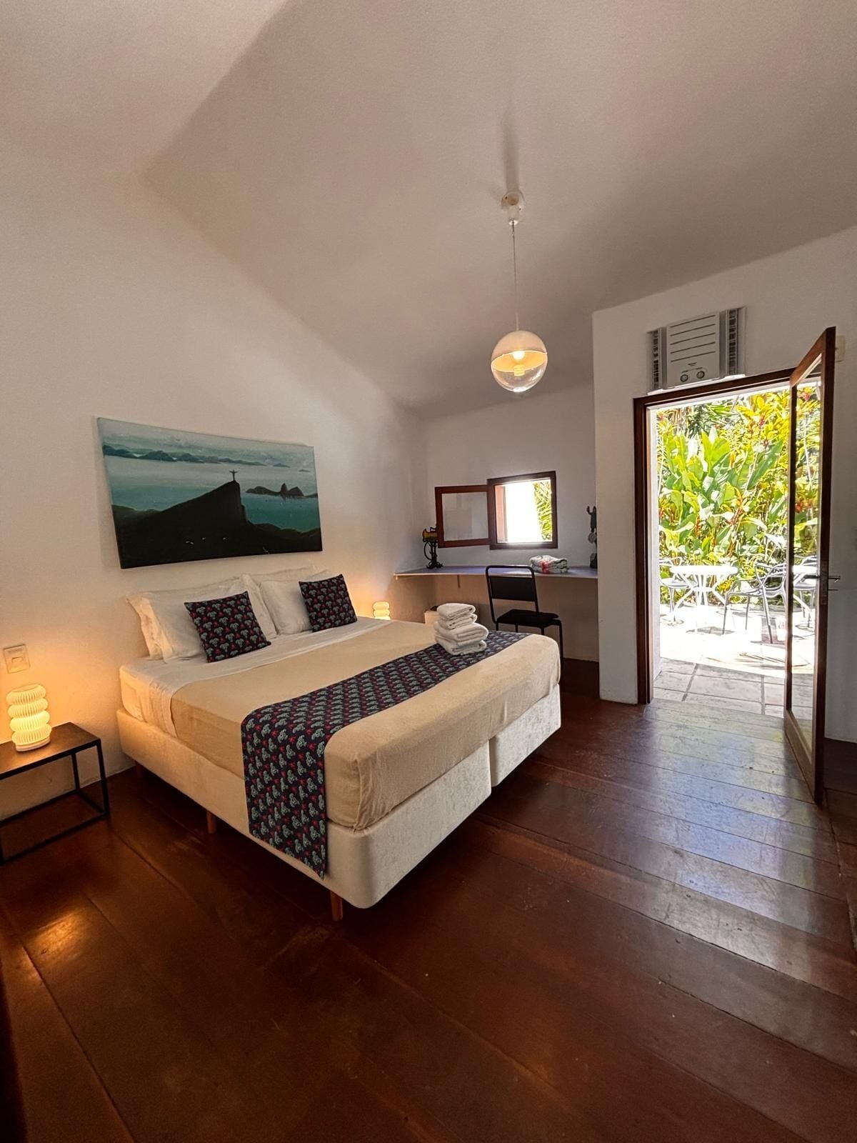 A bedroom with a bed, bedside lamp, and a painting on the wall.