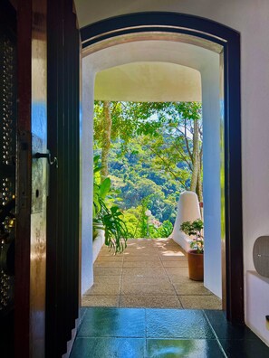 An arched doorway leading to a terrace with a view of a forested hillside. - Les Jardins de Rio  (Rio de Janeiro)