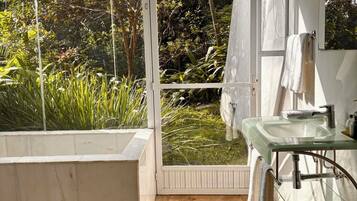 Ein Badezimmer mit einer gläsernen Dusche, einer weißen Badewanne und einem Glaswaschbecken.