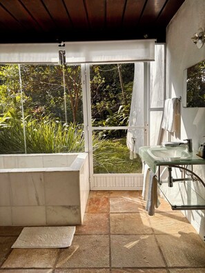 A bathroom with a glass-enclosed shower, a white bathtub, and a glass sink. - Les Jardins de Rio  (Rio de Janeiro)