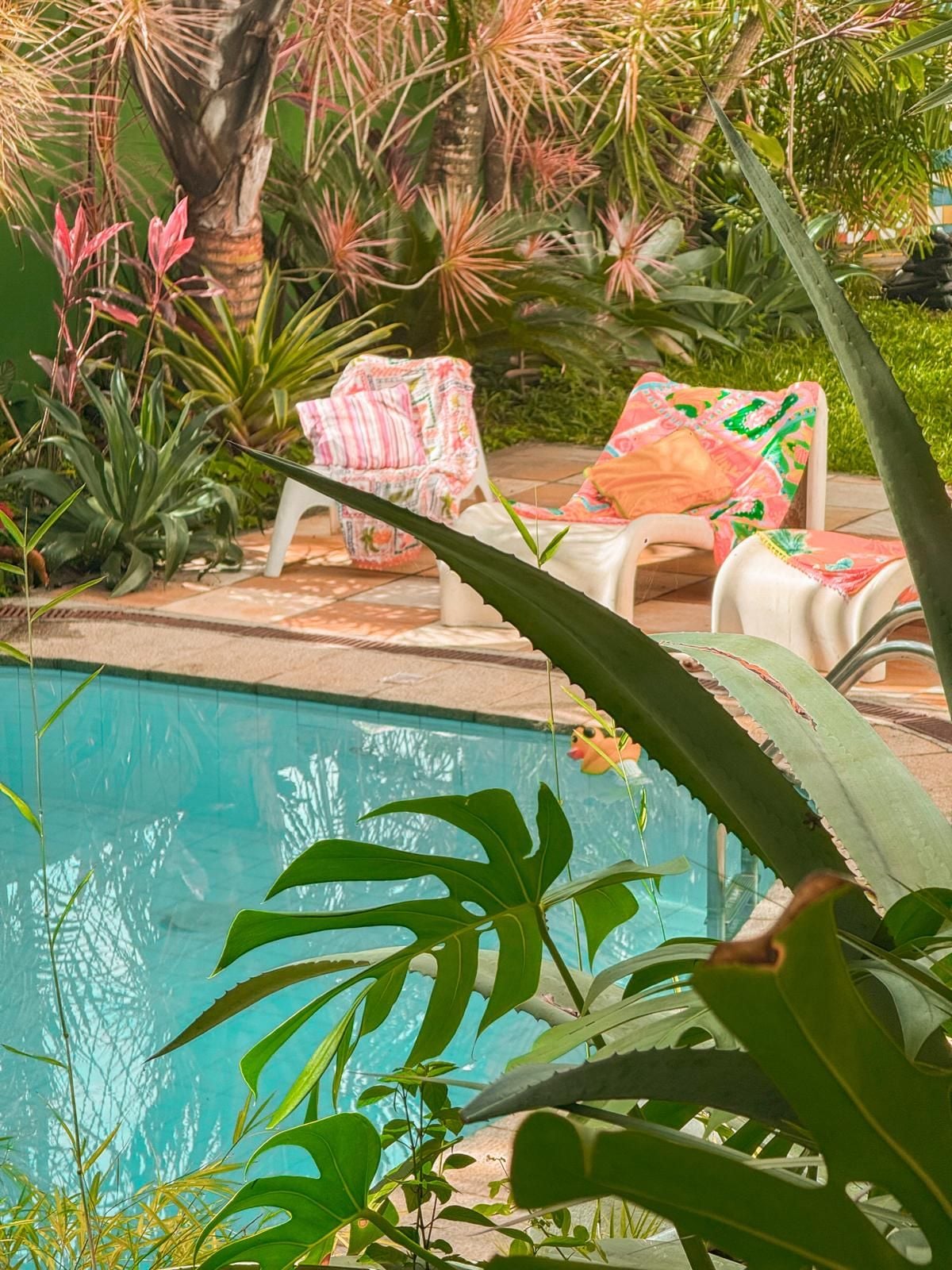 A poolside area with lounge chairs and tropical plants.