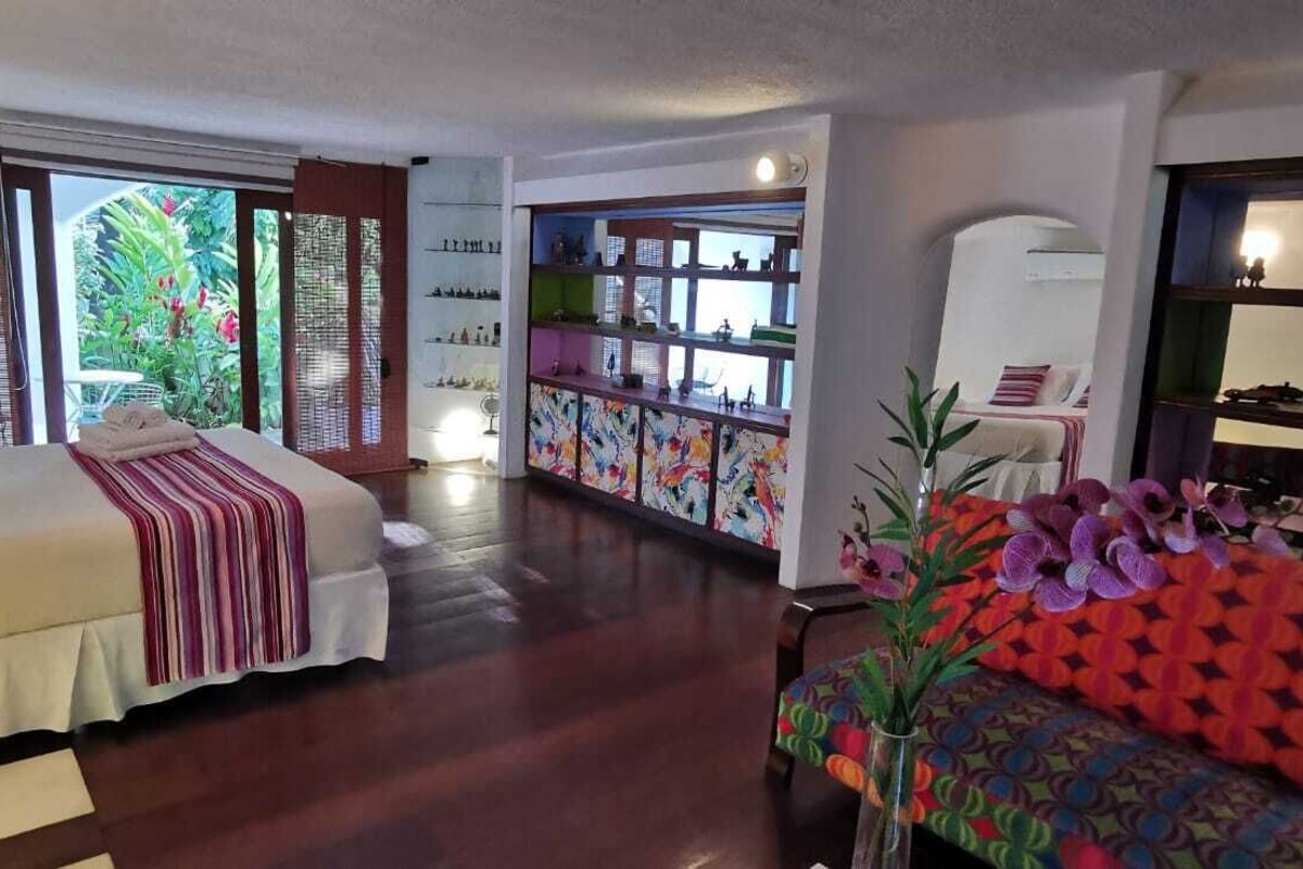 Une chambre d’hôtel avec un lit, un canapé, une télévision, une bibliothèque et une vue sur l’extérieur.