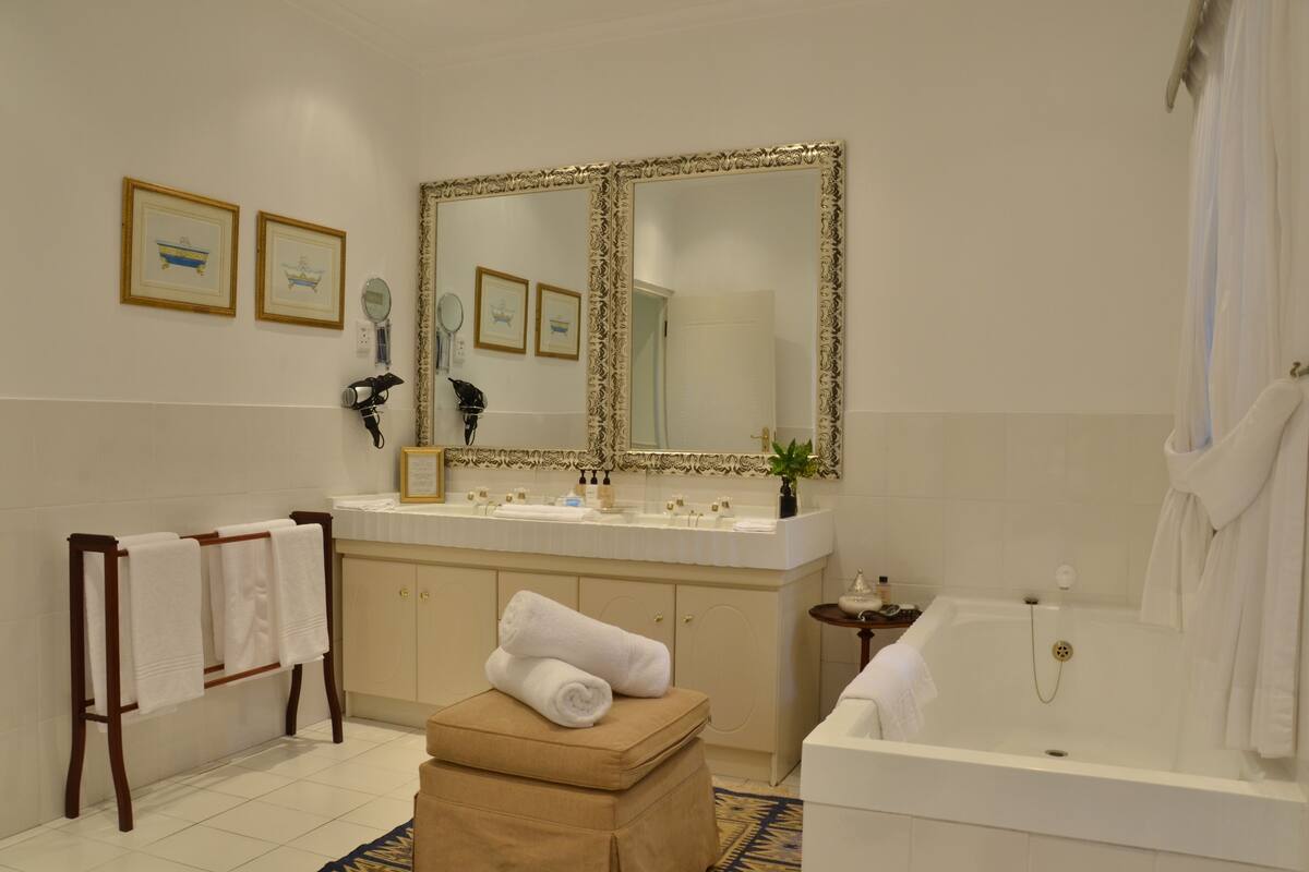 A bathroom with a large mirror, a bathtub, a vanity with a sink, and a towel rack.