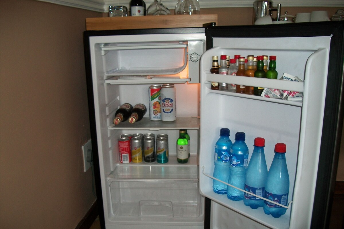 Un refrigerador con estantes llenos de diversas bebidas, incluyendo latas y botellas.
