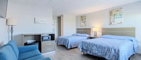 A hotel room with two beds, a desk, a chair, and artwork on the walls.