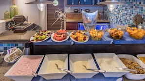 A buffet with various food items including fruits, vegetables, and different types of spreads.