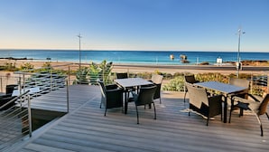 A deck with outdoor seating overlooking a beach.