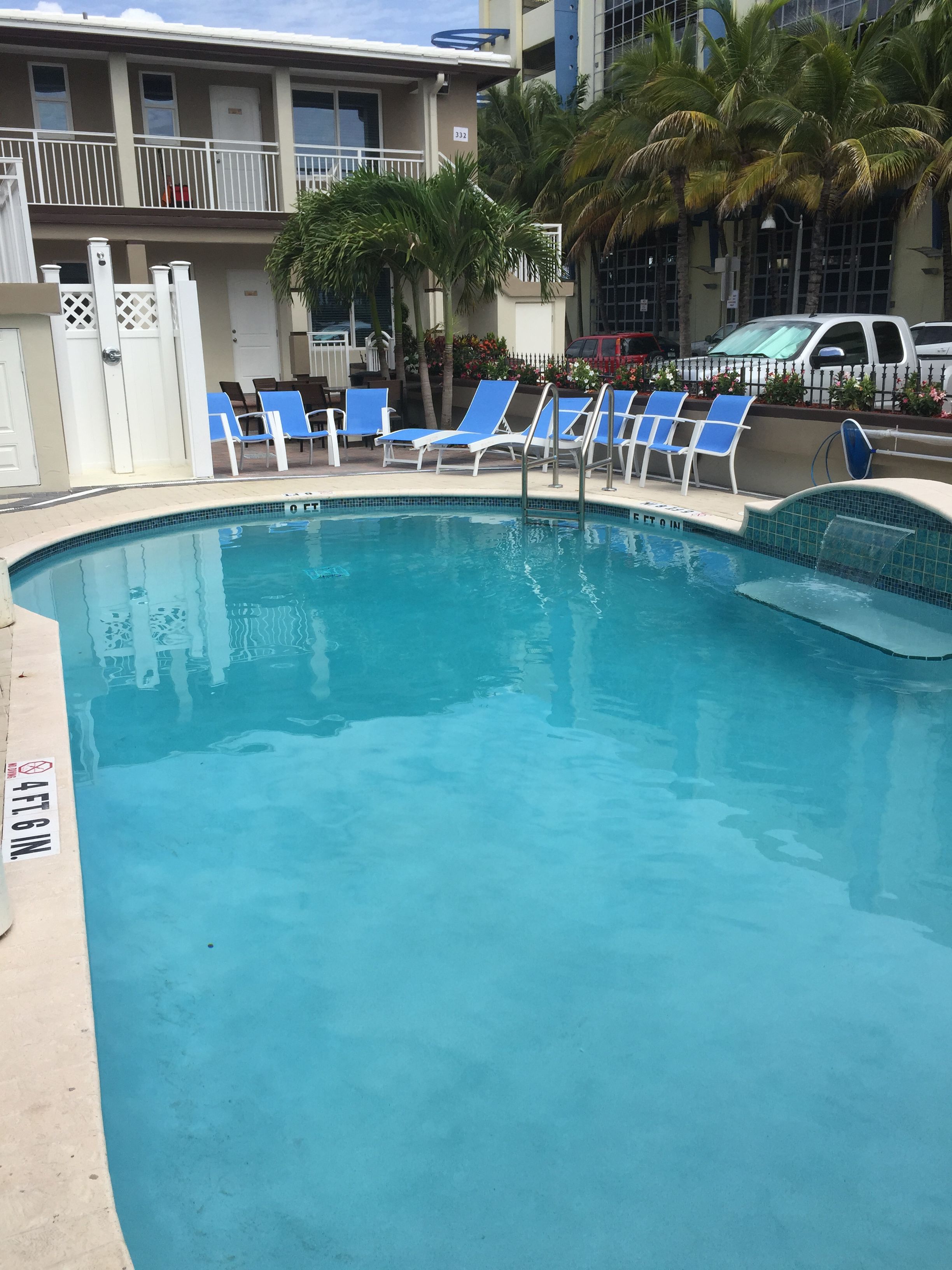 A swimming pool with blue lounge chairs and a white fence.