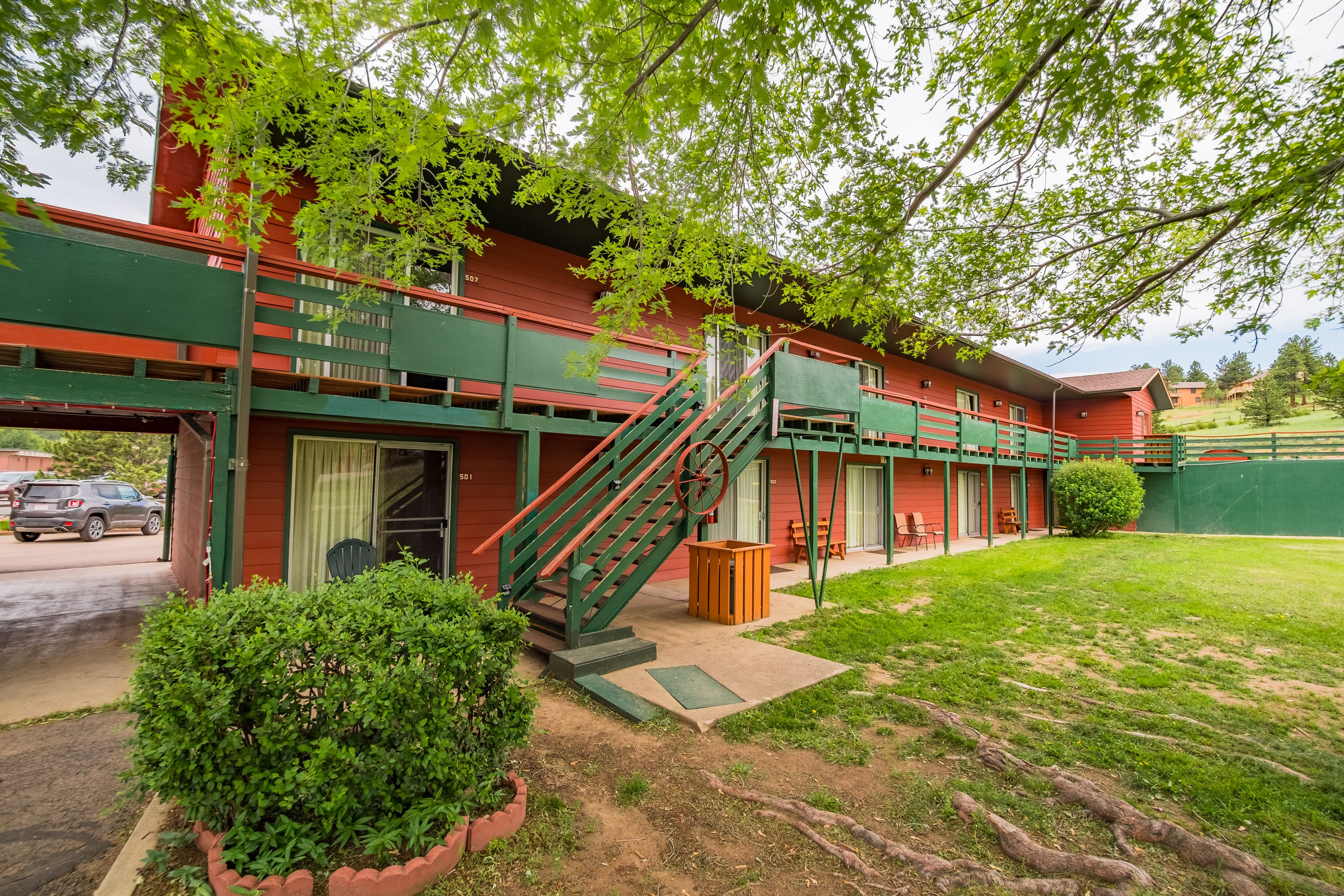 Un edificio rojo con una escalera verde y un pequeño jardín.
