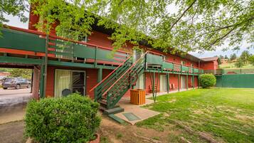 Un edificio rojo con una escalera verde y un pequeño jardín.