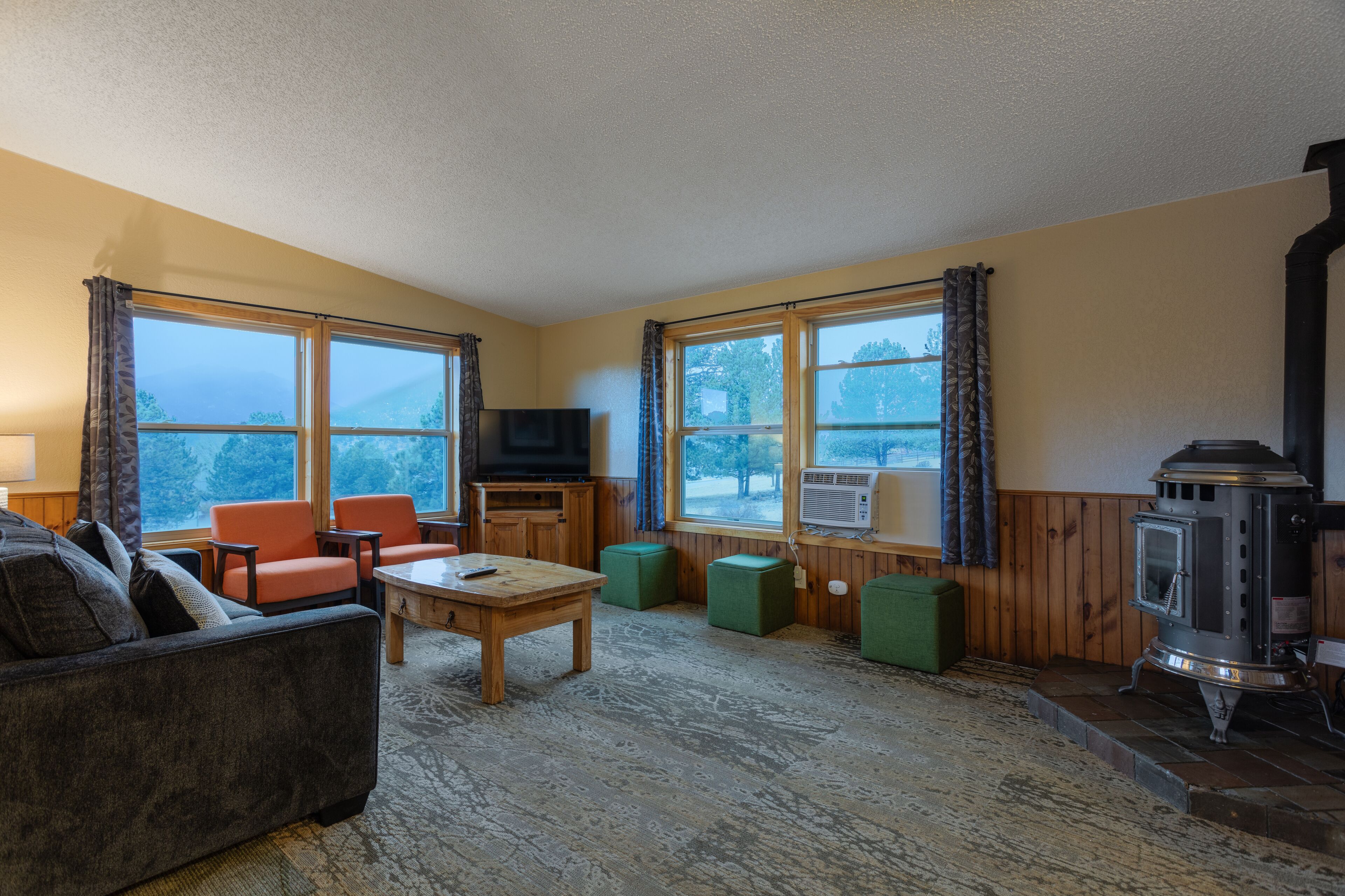 Ein gemütliches Wohnzimmer mit einer Couch, Sesseln, einem Fernseher und einem Kaminofen.