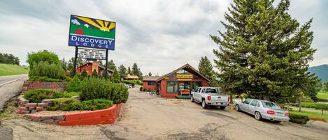 Señal de Discovery Lodge, una cabaña de troncos y vehículos estacionados.
