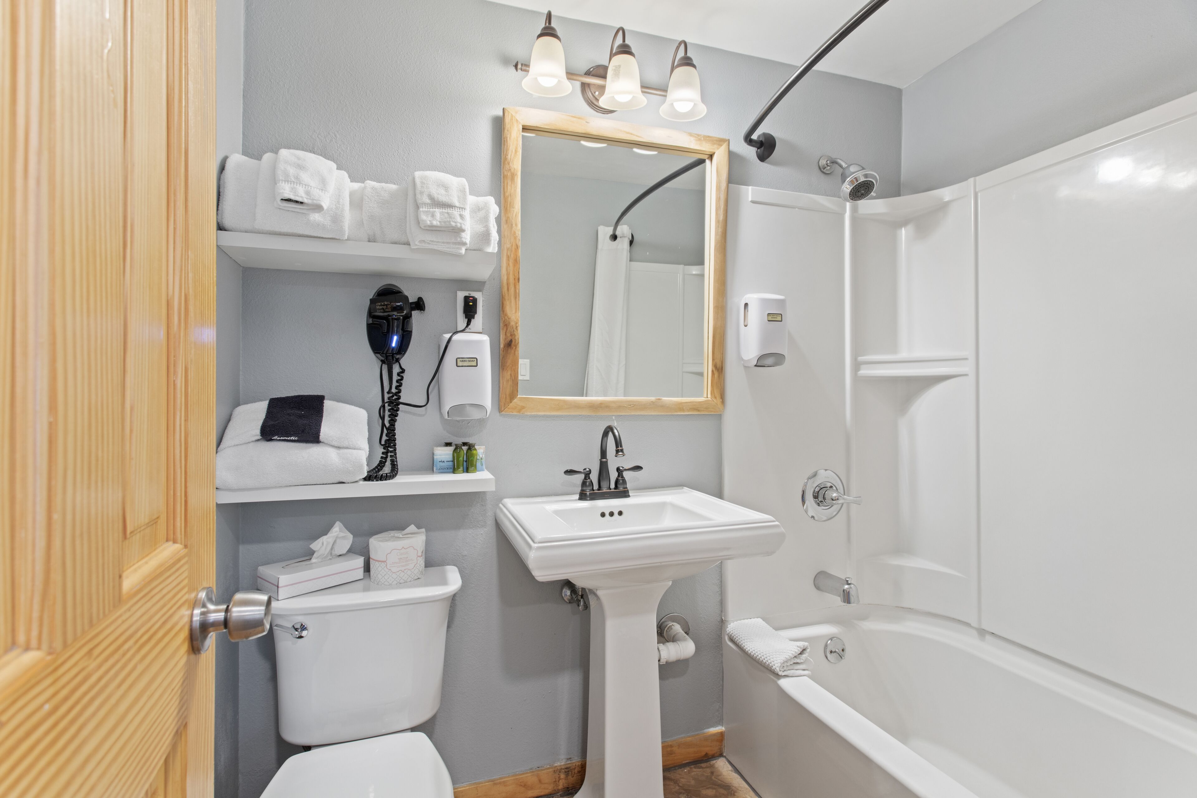A bathroom with a white sink, a mirror, a shower, and a toilet.