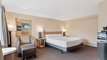 A hotel room with a bed, a chair, a desk, a mirror, and a TV.