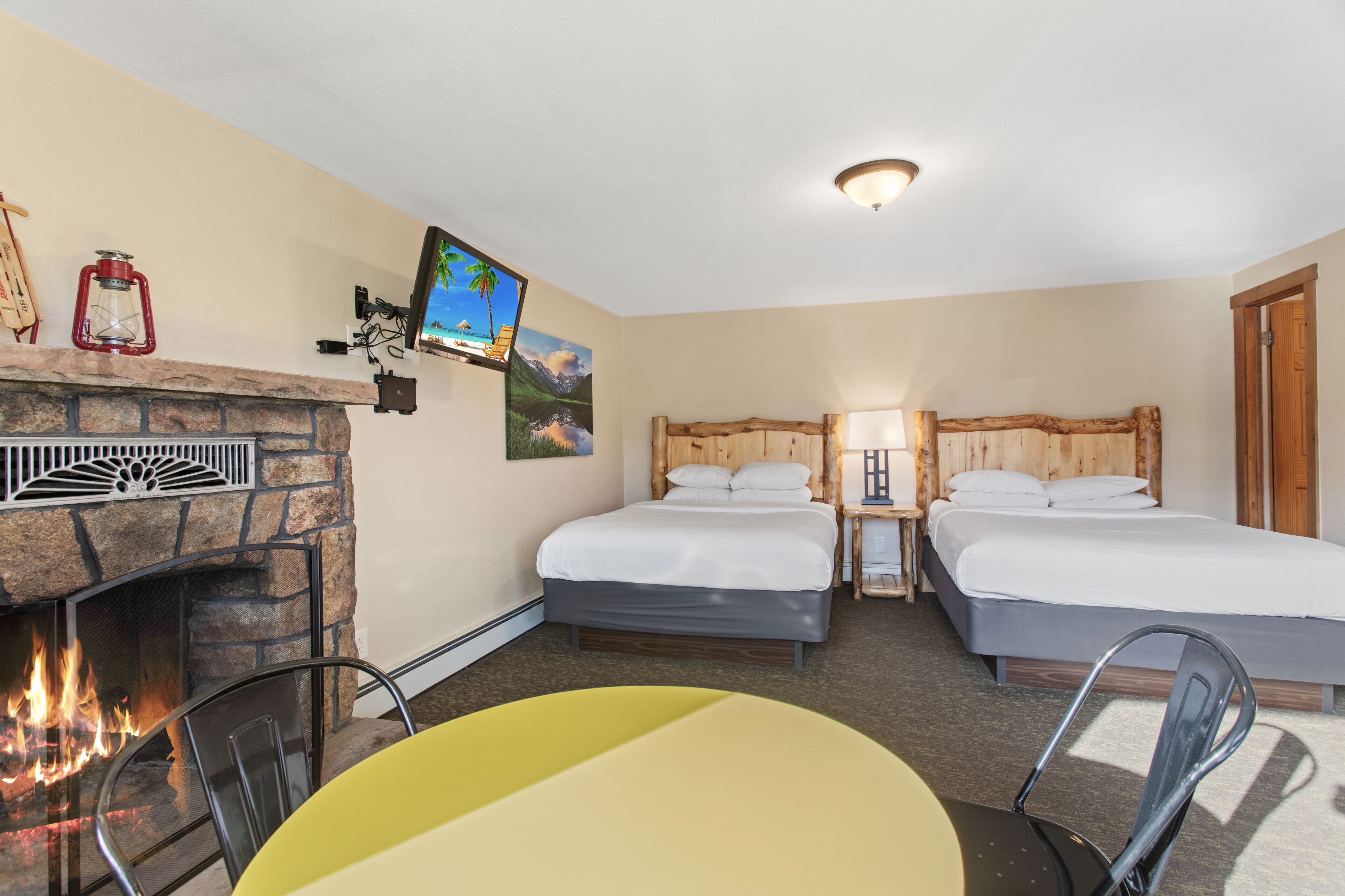A room with a fireplace, two beds, a TV, and a table.