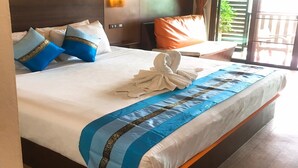 Habitación de hotel con una cama grande, una mesita de noche, una lámpara y vistas al exterior.
