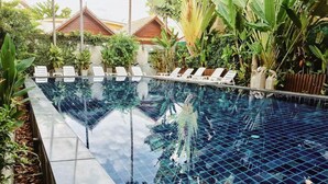 A clear, rectangular swimming pool with white lounge chairs arranged along its length. - BB Mantra (Chiang Mai)