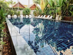 A clear, rectangular swimming pool with white lounge chairs arranged along its length. - BB Mantra (Chiang Mai)
