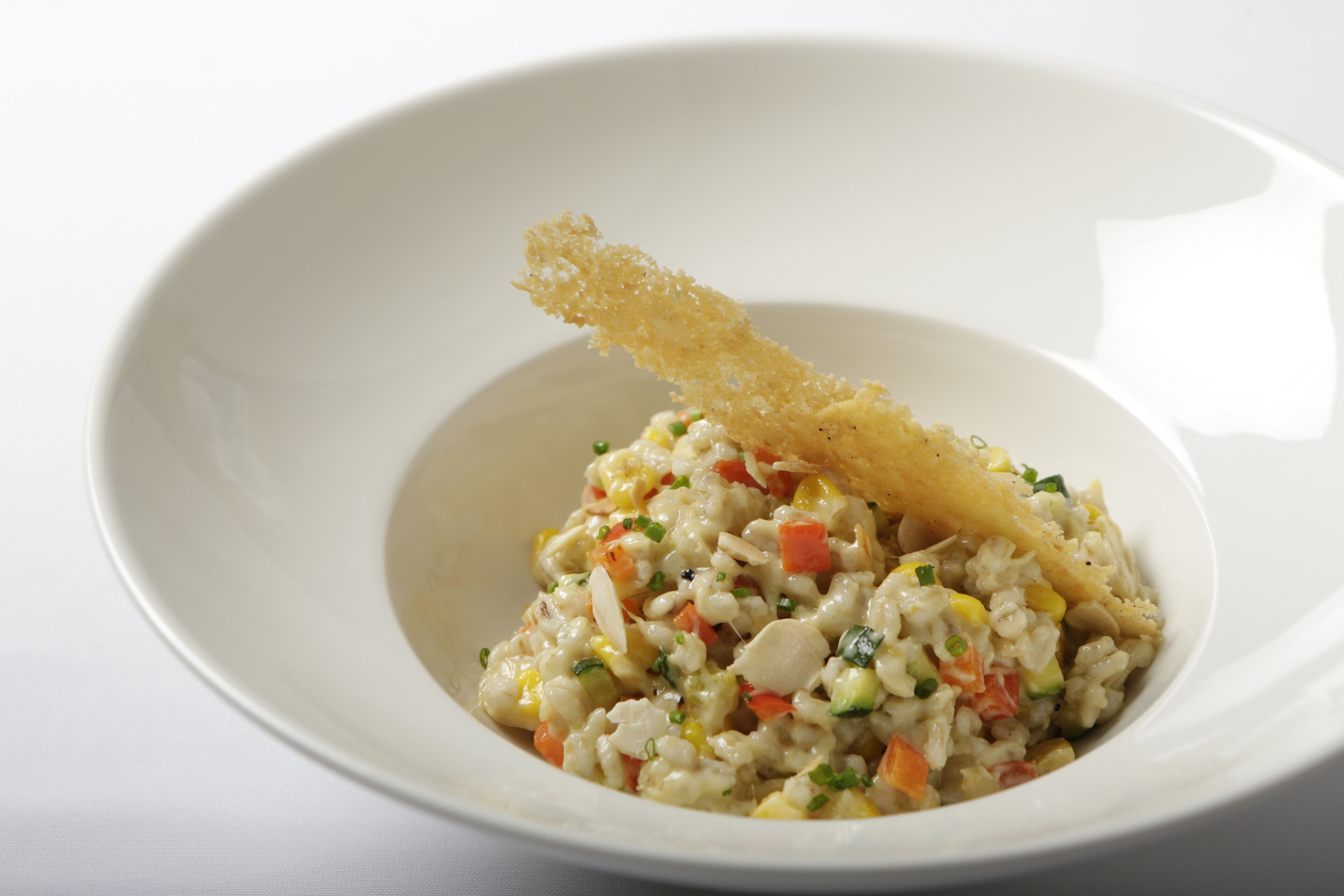 A bowl of rice salad with vegetables and a crispy garnish.