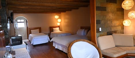 Ein gemütliches Zimmer mit zwei Betten, Holzboden, Steinwänden und einem Korbstuhl.