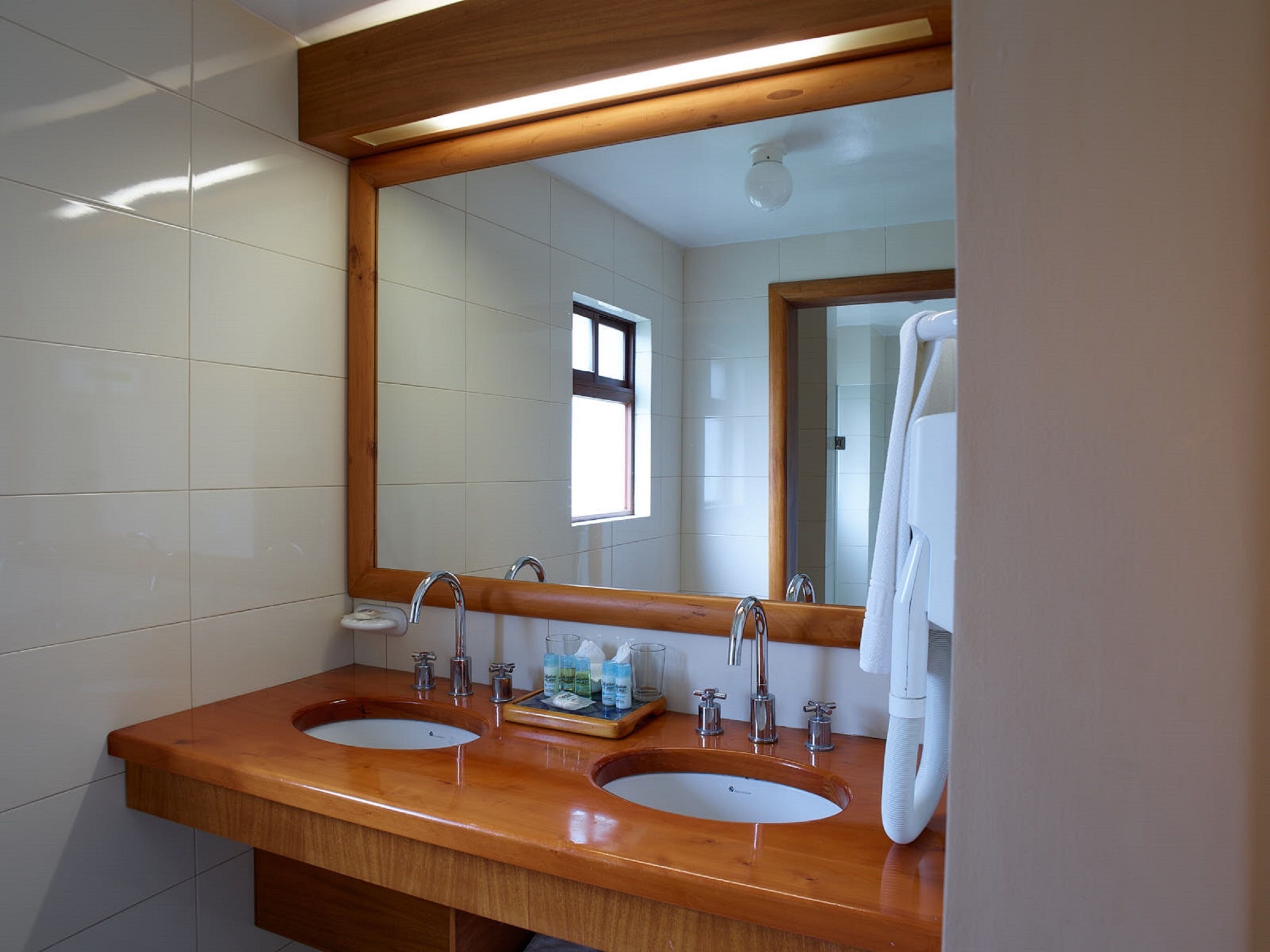 Een badkamer met twee wasbakken, een spiegel en een handdoekhouder.