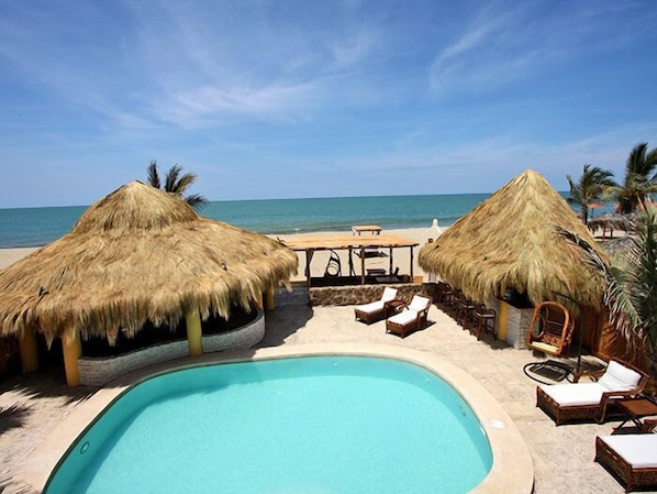 Una piscina al aire libre, sombrillas, sillones reclinables de piscina