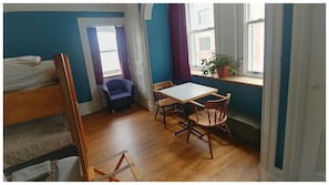 A room with bunk beds, a small table with chairs, a potted plant, and a window with curtains. - Auberge Internationale de Québec - Hostel (Québec City)