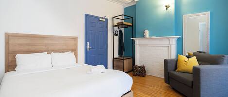 A bedroom with a bed, a blue door, a fireplace, and a grey sofa.