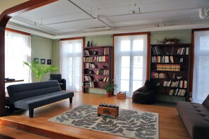 A living room with a sofa, a coffee table, and two bookshelves filled with books. - Auberge Internationale de Québec - Hostel (Québec City)