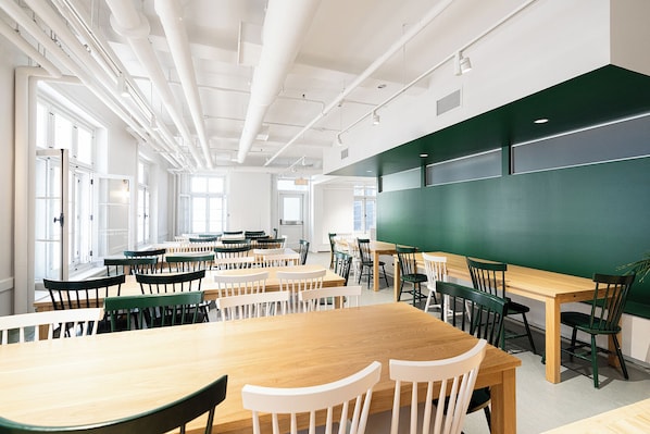 A classroom with tables and chairs, a large green chalkboard, and windows allowing natural light. - Auberge Internationale de Québec - Hostel (Québec City)