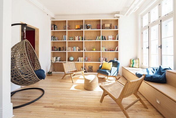 A modern living room with a large bookshelf, comfortable seating, and a hanging chair. - Auberge Internationale de Québec - Hostel (Québec City)