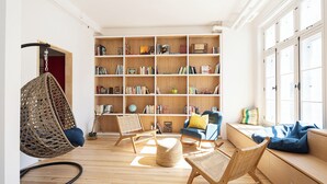 A cozy reading nook with a large bookshelf, wicker chairs, and a window seat. - Auberge Internationale de Québec - Hostel (Québec City)