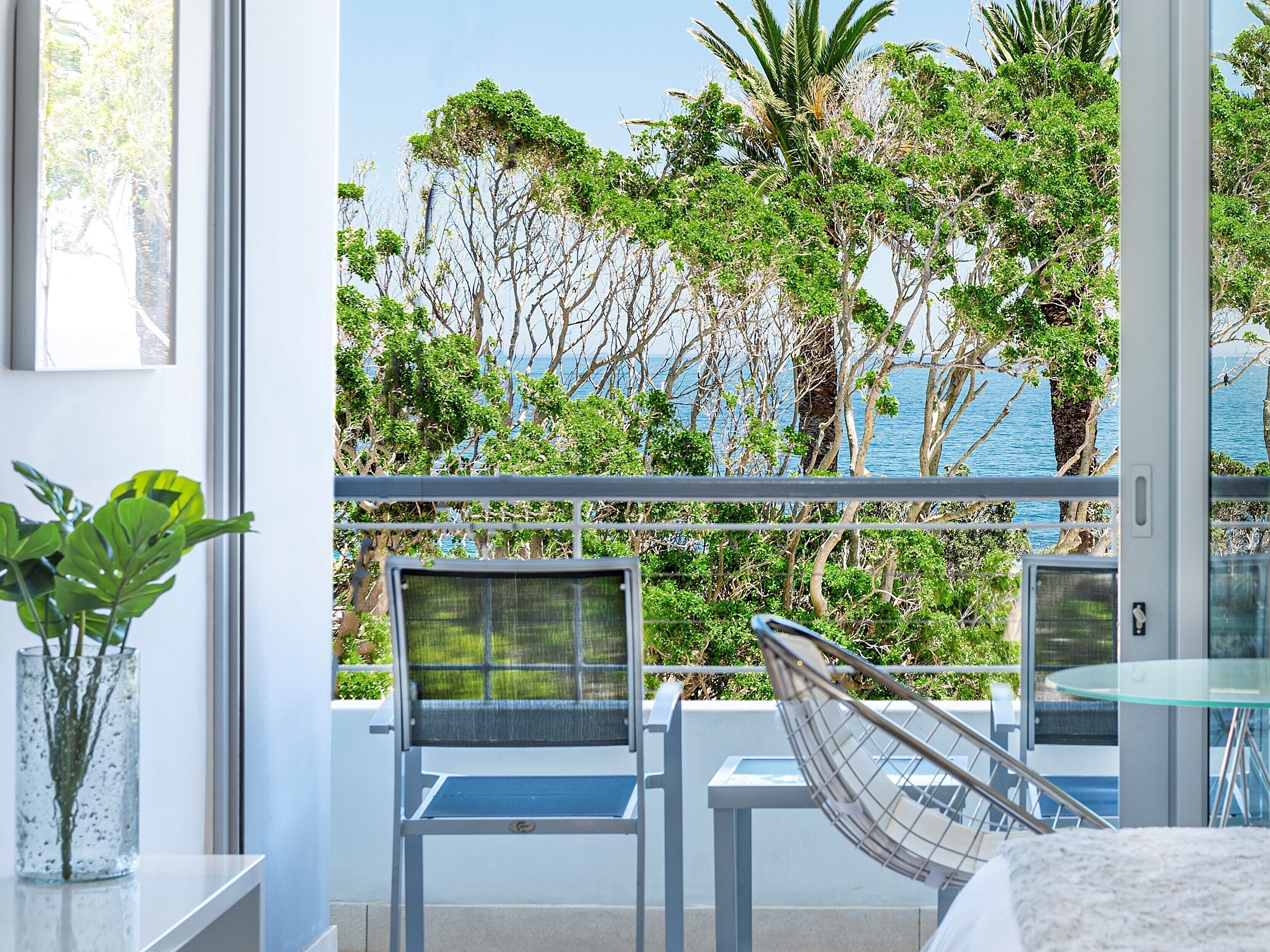 Un balcon donnant sur un jardin luxuriant et la mer.